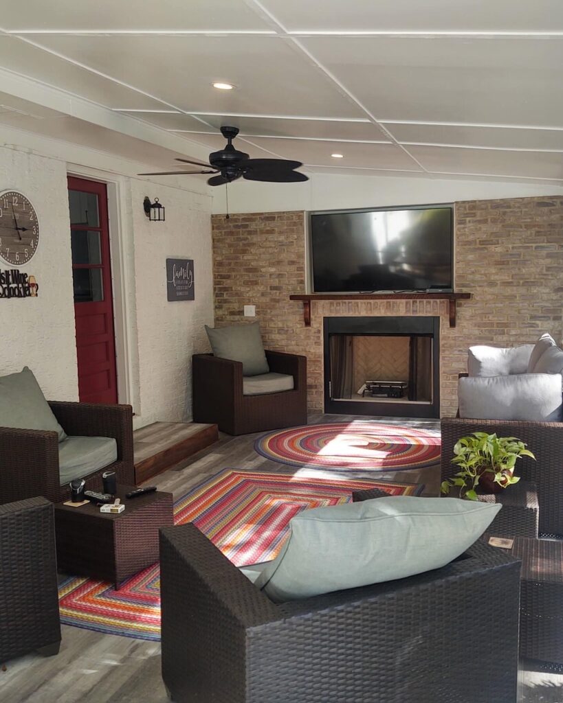 Enclosed porch with a bar counter, seating, a mounted TV and a ceiling fan