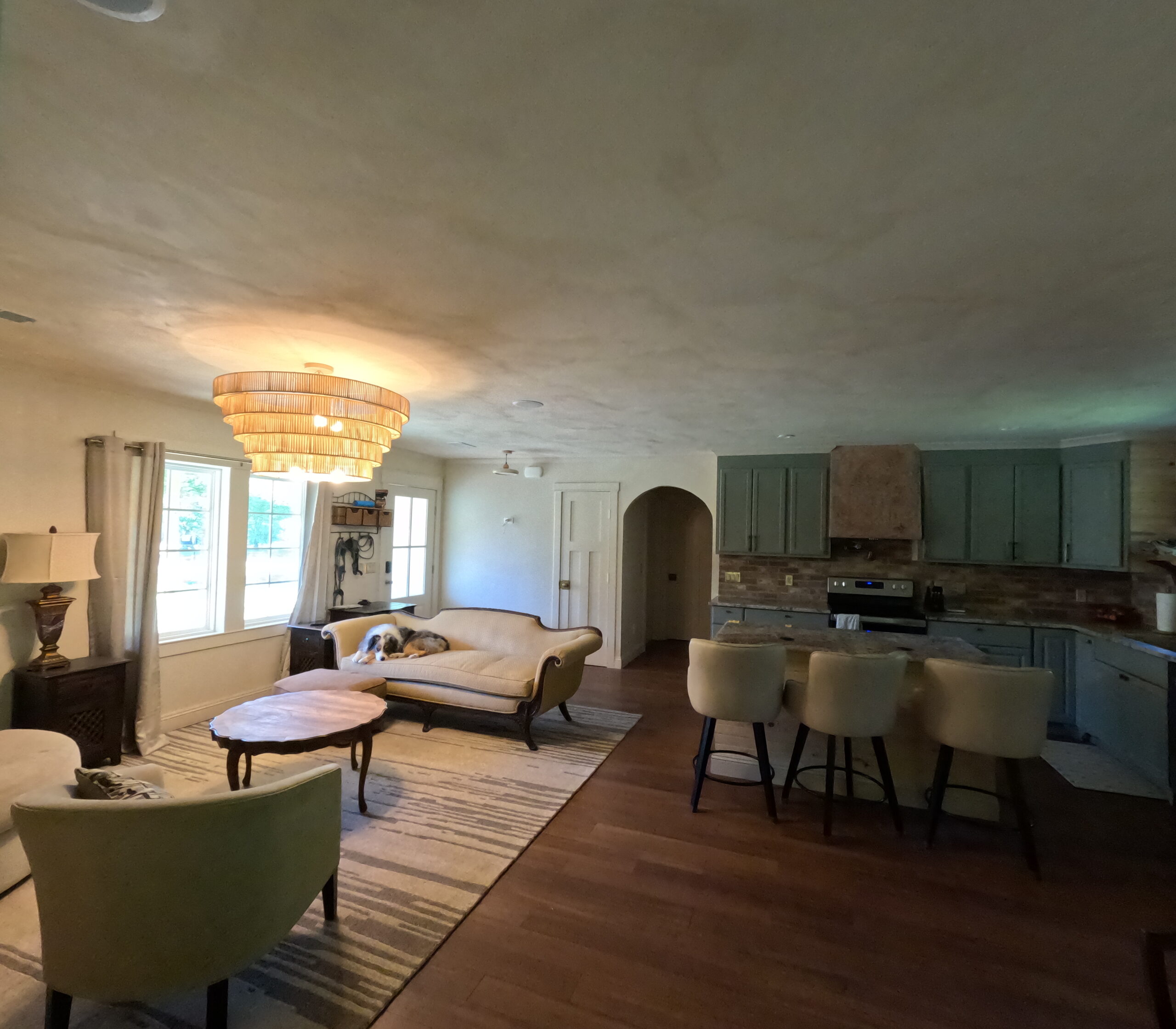 Open great room with a living area, a dining table and the kitchen beyond