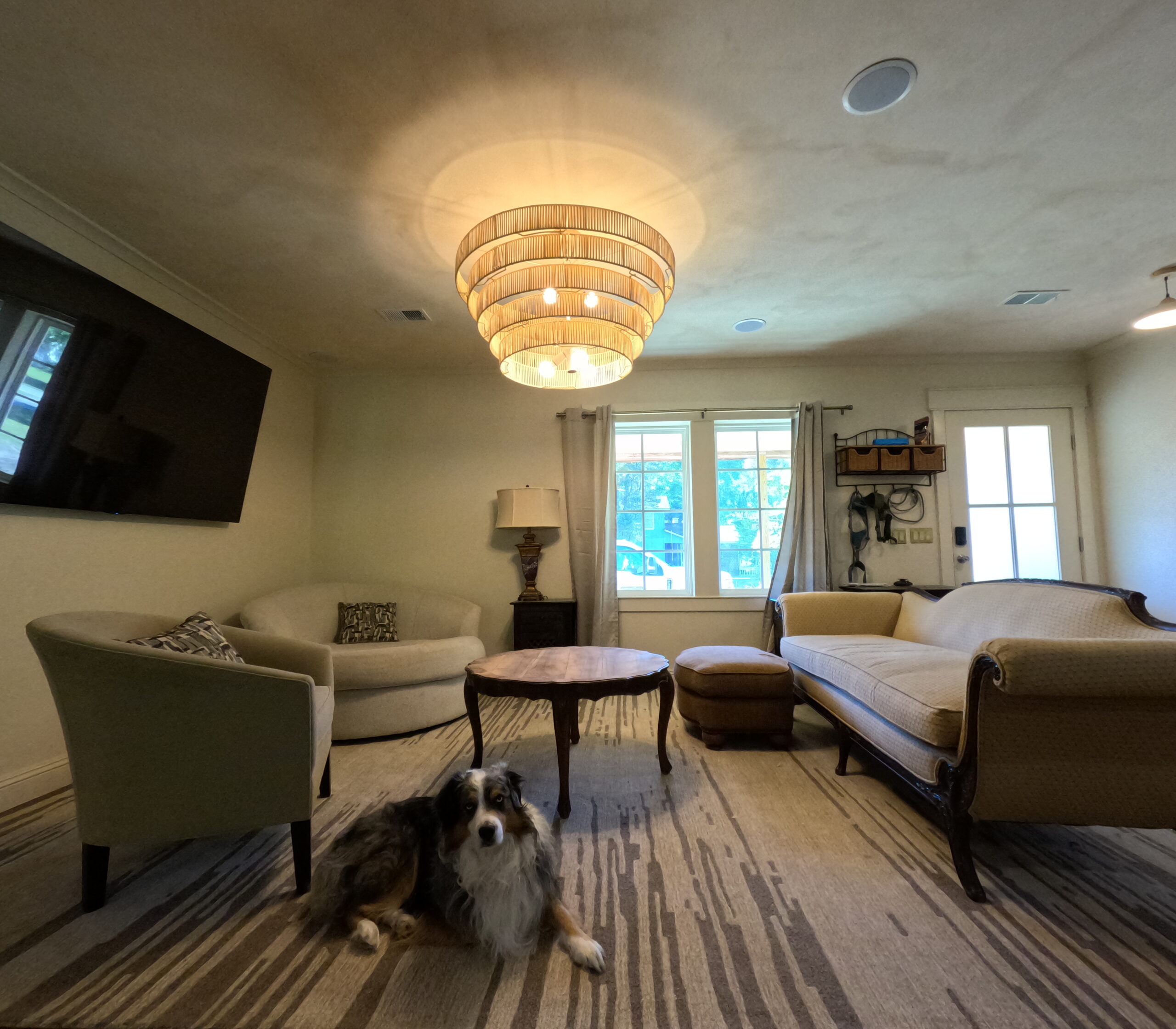 Living room with a limewash ceiling, wood flooring and a tiered pendant light