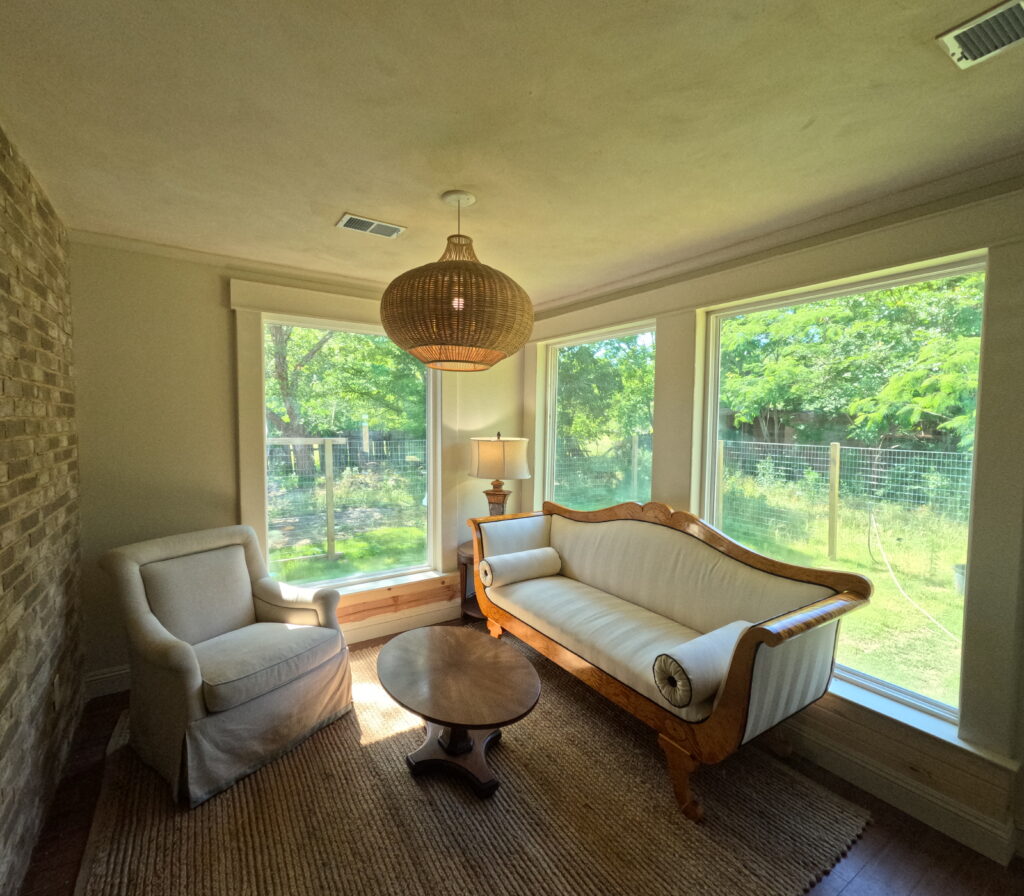 Sunroom addition with large picture windows, an exposed brick wall and a woven pendant light