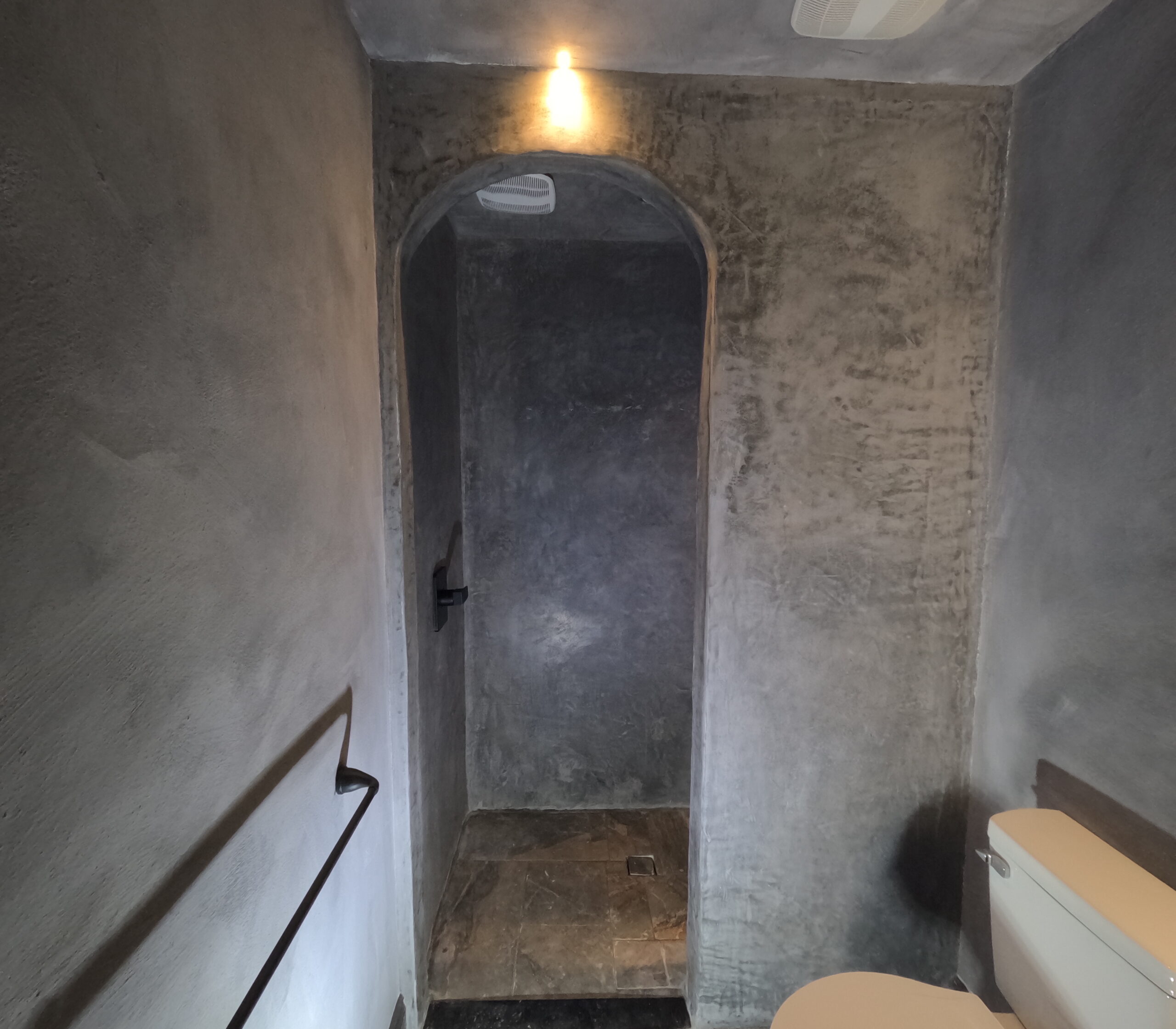 Tadelakt bathroom with an arched niche Bathroom with grey tadelakt plaster walls and an arched niche