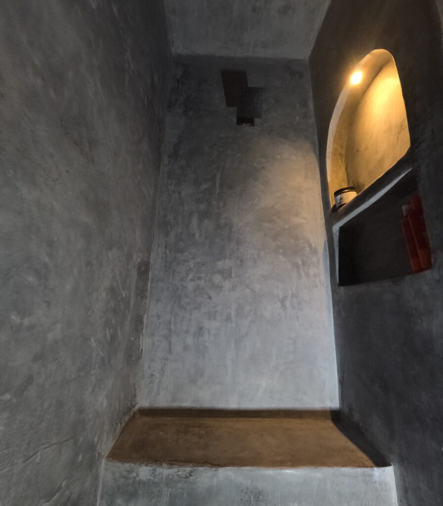 Grey tadelakt shower with a lit niche and a built-in bench