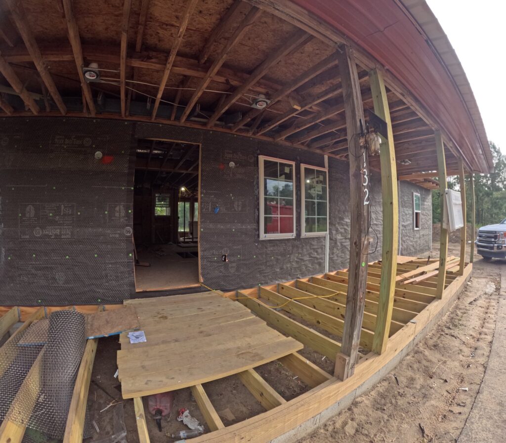 In-progress photo: new porch deck framing and an open ceiling with exposed rafters during the rebuild