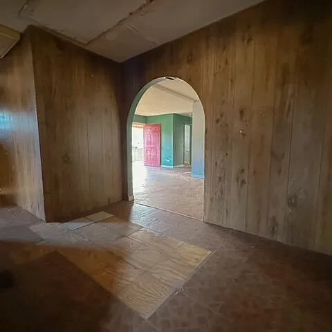 Before: an arched opening in a wood-panel wall